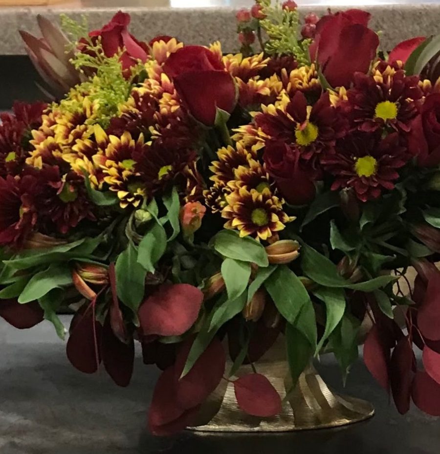 Autumn centerpiece in a gold pedestal bowl with burgundy roses, mums and eucalyptus